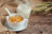 A white bowl filled with cornflakes cereal and a spoon, next to a glass pitcher of milk and wheat stalks.