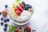 A bowl of yogurt with granola and fresh berries, including strawberries, blueberries, blackberries, and banana slices